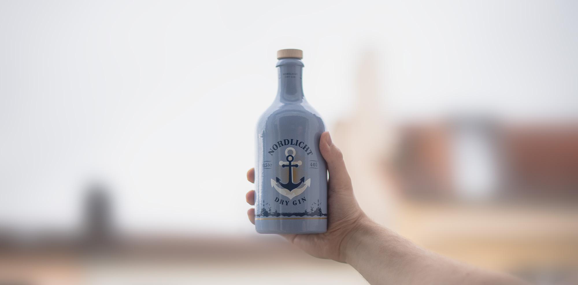 Stimmungsvolles Hero-Bild, das eine Flasche Nordlicht Dry Gin auf einer Theke darstellt, umgeben von einer coolen Baratmosphäre voller Charakter.