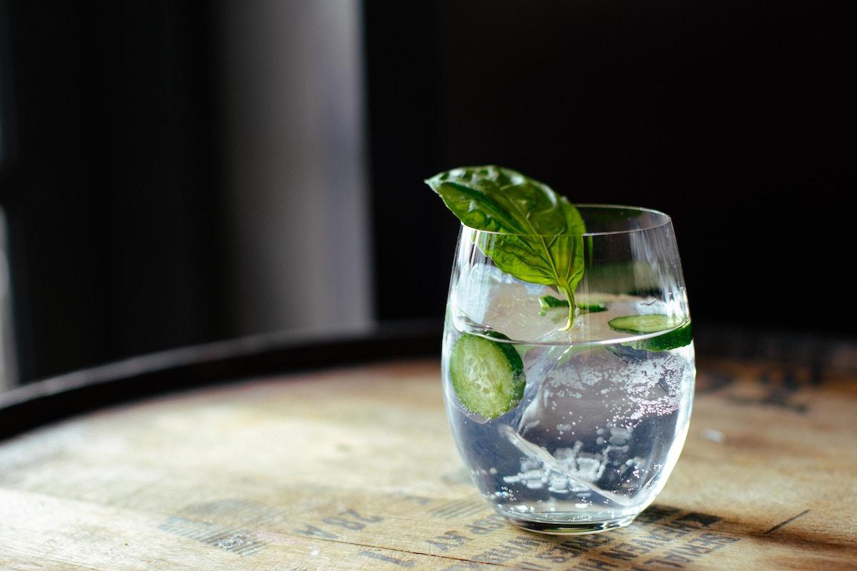 Ein Glas mit Eiswürfeln und einer Scheibe Zitrone, gefüllt mit dem kräftigen, würzigen Geschmack des Ruby of Rangoon Original London Dry Gins – ein Genuss für alle Sinne.